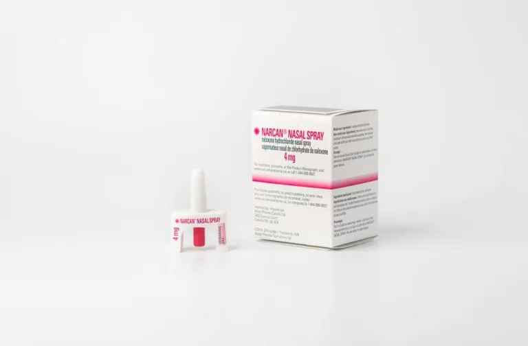 A box and single-dose container of Narcan nasal spray are displayed against a white background. The packaging includes red and purple text.